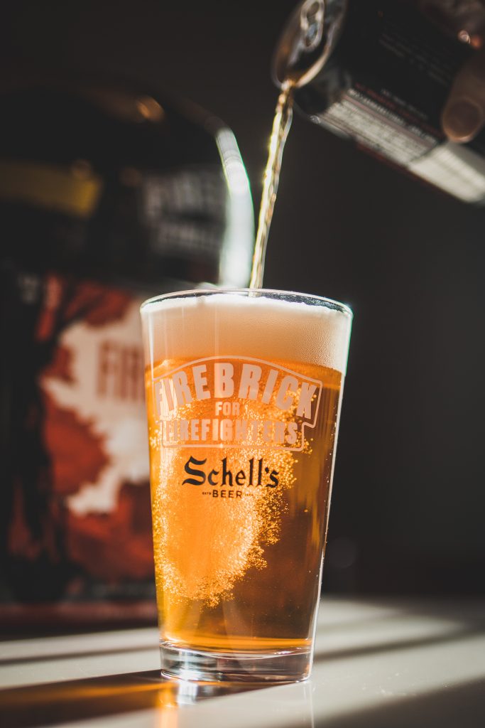 Pouring beer from a can into a branded Firebrick for Firefighters pint glass