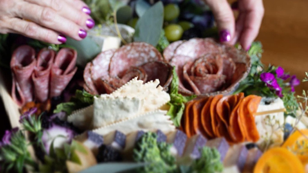 a woman's hands working on creating a charcuterie spread that includes meats and cheeses